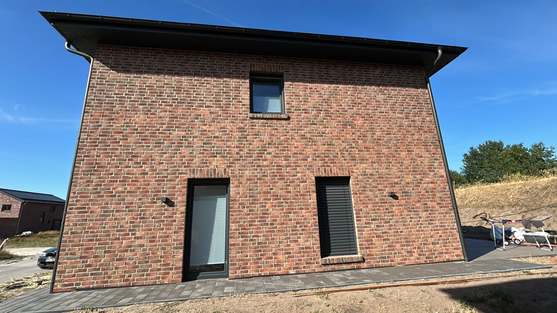 Einfamilienhaus mit Carport in Lohne, Giebelansicht mit Klinkerfassade vor blauem Himmel
