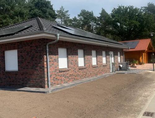 Winkelbungalow mit Walmdach in Varloh, Fensterfront der Klinkerfassade