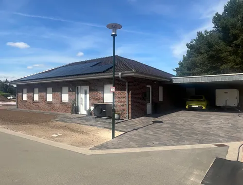 Winkelbungalow mit Walmdach in Varloh, Straßenansicht mit Carport und Photovoltaikanlage
