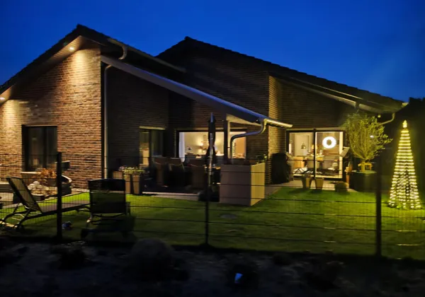 Bungalow mit Satteldach in Varloh in der blauen Stunde mit beleuchteter Terrasse
